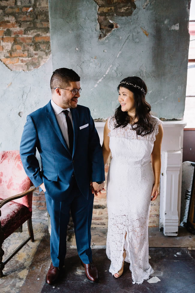 Newlyweds stand in front of dilapidated wall at their industrial wedding venue Newlyweds stand in front of dilapidated wall at their industrial wedding venue