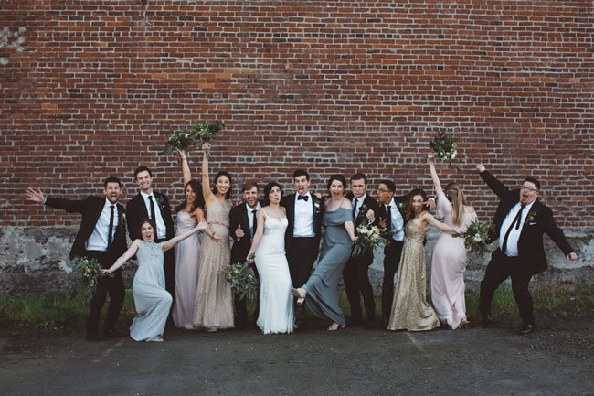 Bridal party poses in front of large brick warehouse Bridal party poses in front of large brick warehouse