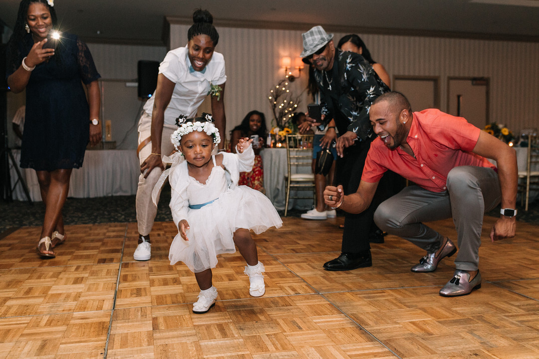 A young flower girl in a flower crown busts a move on the wedding dance floor