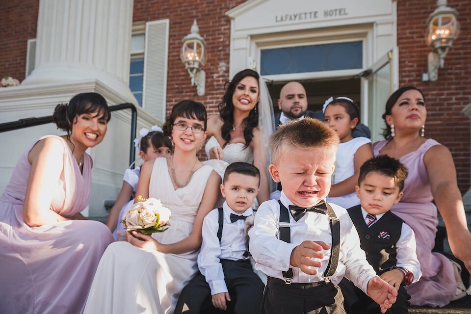 A cute young ringbearer crying as he walks away from a formal wedding portrait