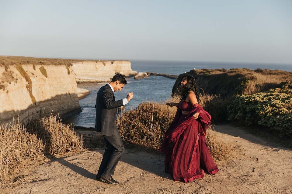 A couple dances in front of the ocean right after getting engaged