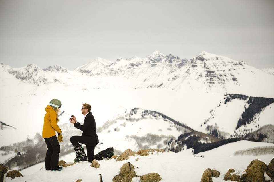An adventurous marriage proposal on skis on a snowy mountaintop