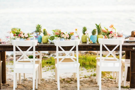 Beach wedding décor idea: Pineapples Wedding reception table on the beach adorned with colorful pineapples