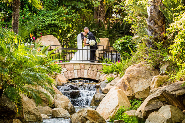 Newlyweds kiss on a bridge at Grand Tradition Estate and Gardens in Fallbrook, CA. Newlyweds kiss on a bridge at Grand Tradition Estate and Gardens in Fallbrook, CA.