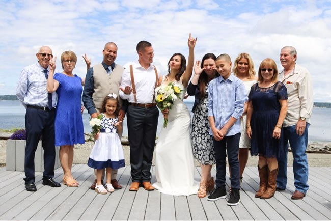 Bride and groom posing with their small group of wedding guests