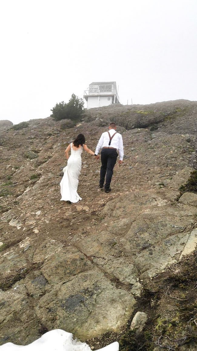 Bride and groom hiking up the side of a mountain