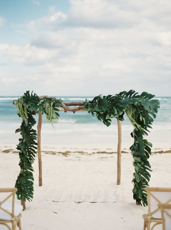 Beach wedding décor idea: Monstera leaf ceremony arch Beach wedding ceremony arch covered with monstera leaves