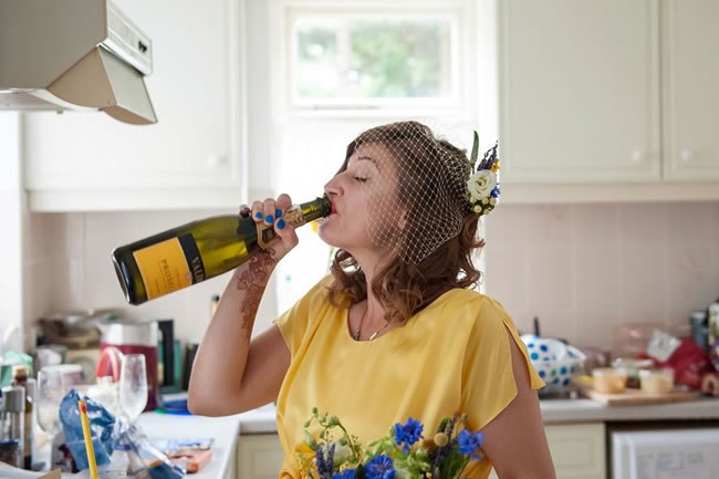A bride-to-be drinking wine straight out of the bottle