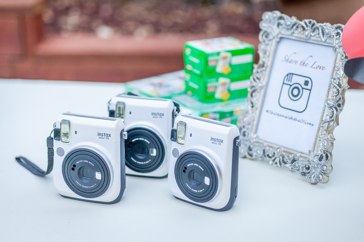 Intax cameras and film set up at a wedding table beside a framed hashtag sign