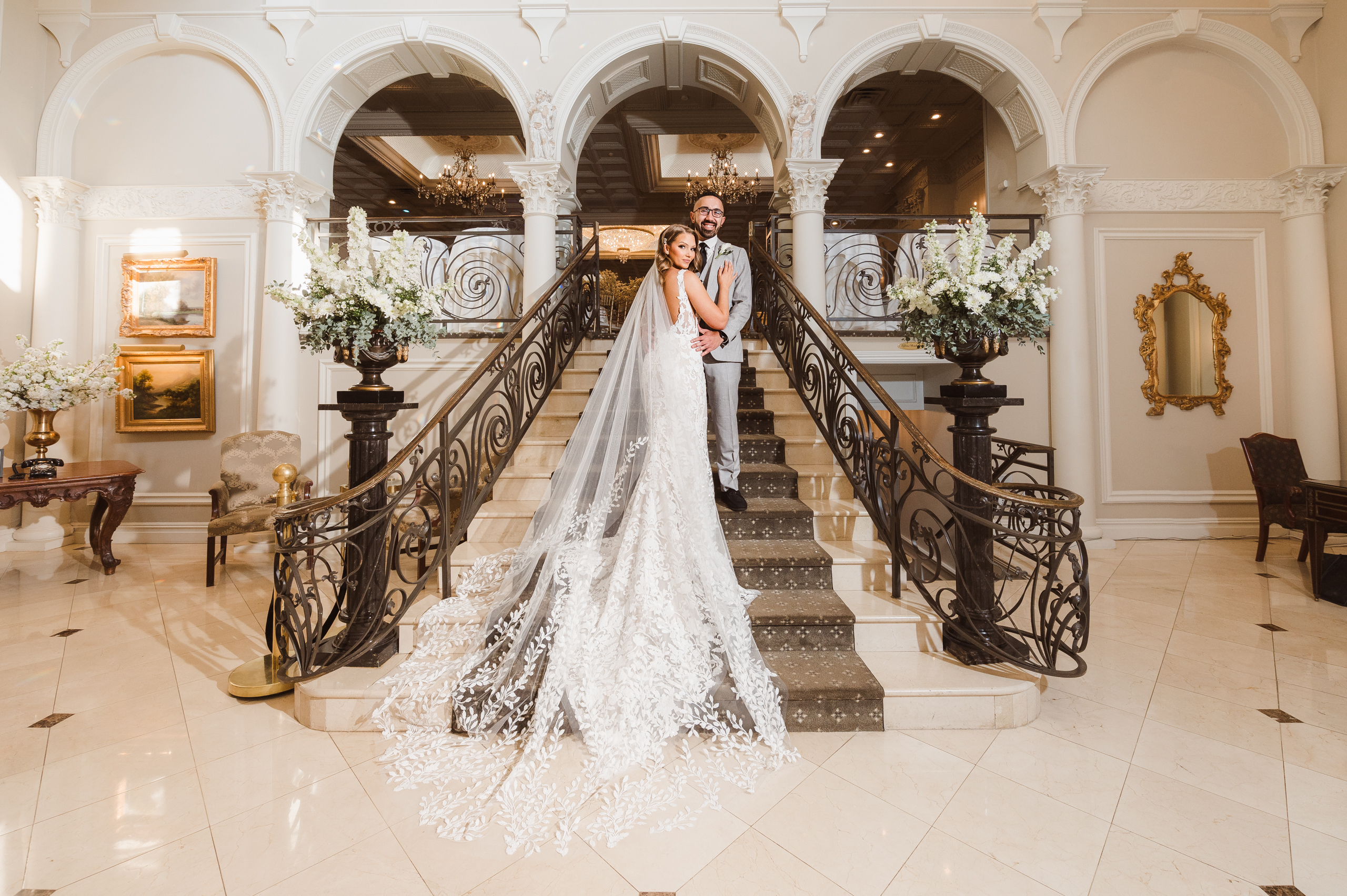 Bride and groom posing together on an ornate staircase at their wedding venue