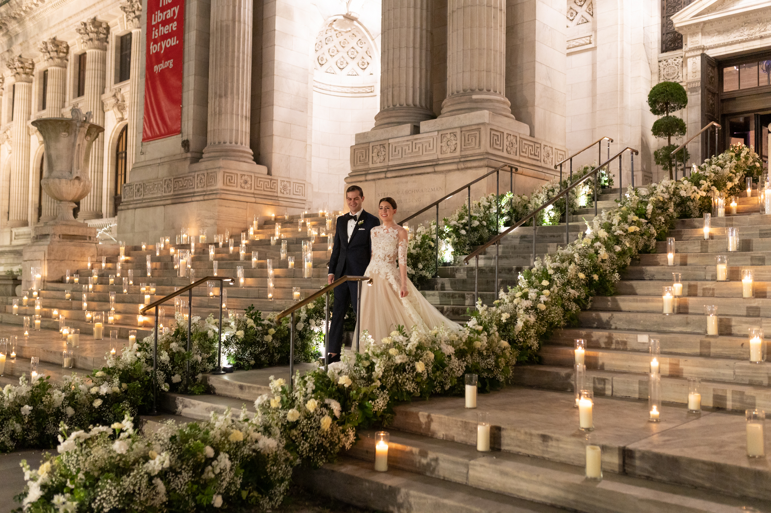 Bride and Groom walking down candle-lit steps outside the New York Public Library.