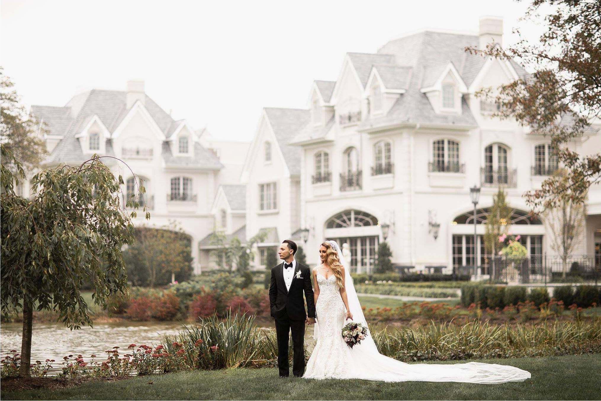 Bride and groom posing outdoors in front of an elegant wedding venue