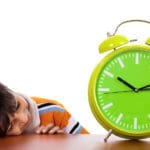 Boy tired of study and sleeping near the clock