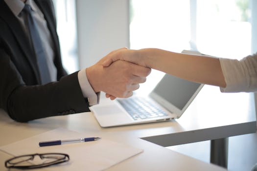 Close-up of a professional handshake over a laptop during a business meeting in an office, trade show exhibit management