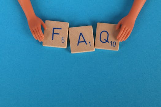 Flat lay of scrabble tiles spelling 'FAQ' with toy hands on a blue background, creating a conceptual image, trade show FAQs