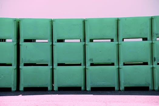 Row of green plastic tubs stacked against a pink wall. Industrial and storage concepts.