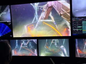The arm of Jason picks up a digital still camera from the seafloor deployed in 2025.