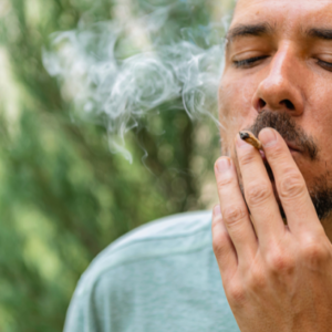 A man closes his eyes as he smokes a legal cannabis joint