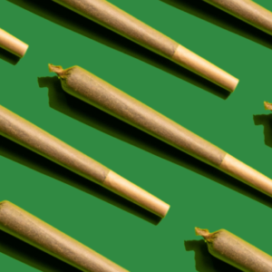 A uniform pattern of preroll marijuana joints on a green background