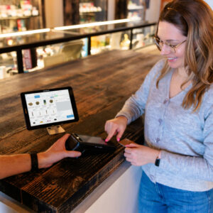 A budtender and customer smiling during a transaction using Cova’s dispensary POS system