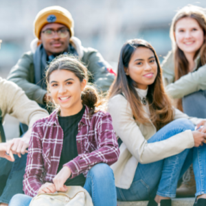 A group of smiling teens poses outdoors for a photo