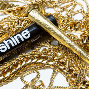 Gold leaf rolling paper beside gold jewelry on a white background