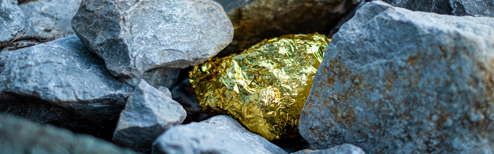 A gold nugget nestled and almost hidden in grey stones in a conflict minerals mine.