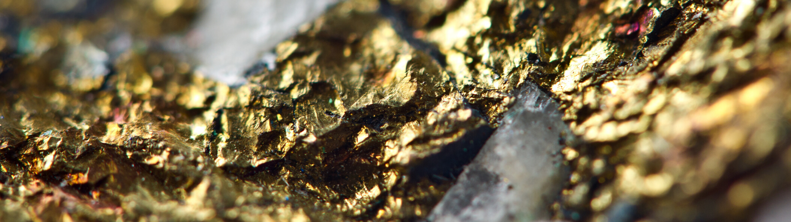 Close up of the conflict mineral gold in its raw, unrefined state mixed with dark stone.