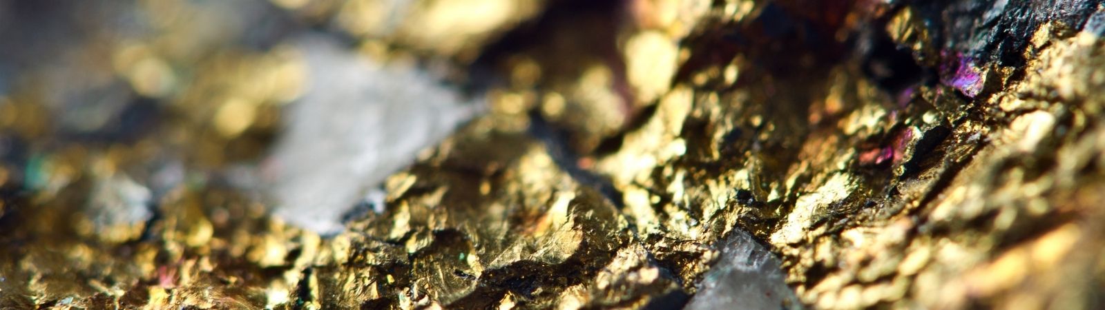 Close up of the conflict mineral gold in its raw, unrefined state mixed with dark stone.