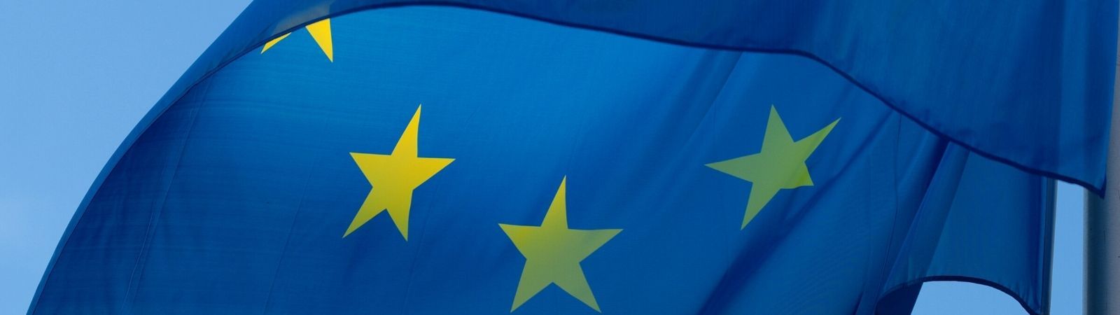 Close up of the EU flag waving in the wind against a bright blue, cloudless sky.