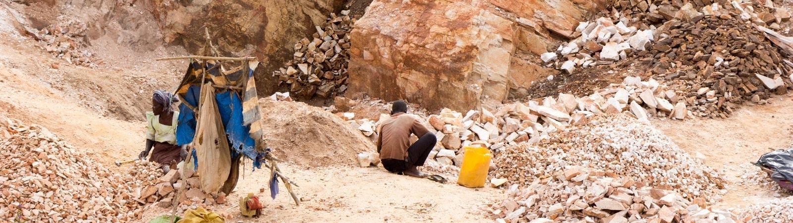 Desert mine on a relentlessly sunny day using modern day slavery with workers in tattered clothes.
