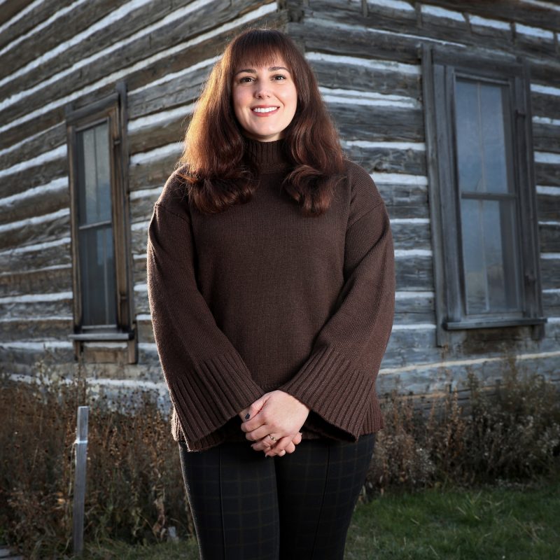 Jane standing outside next to the wooden Tinsley House.