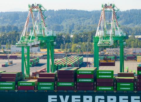 Aerial shot of cranes moving containers off a ship.