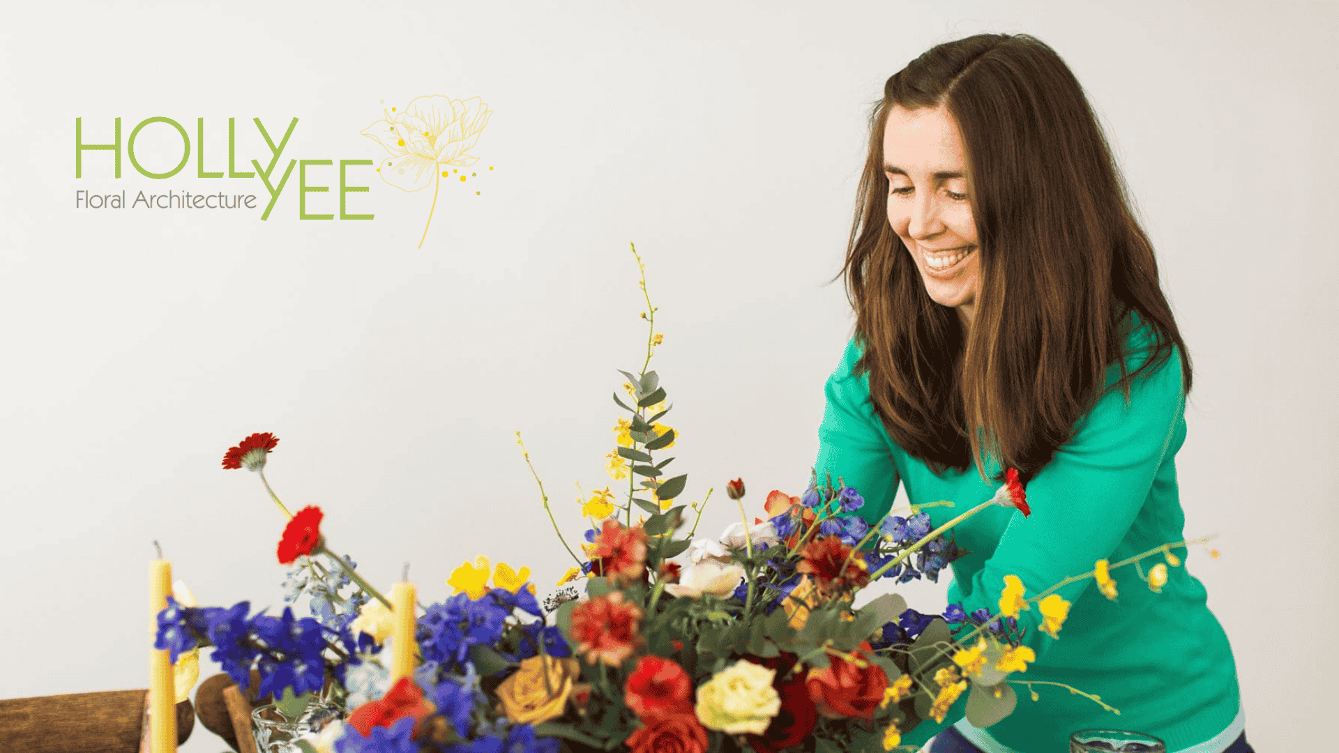 Woman with long, brown hair grins as she assembles beautiful bouquet of colorful flowers