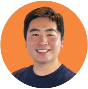 Man with short, black hair wearing navy t-shirt smiles warmly