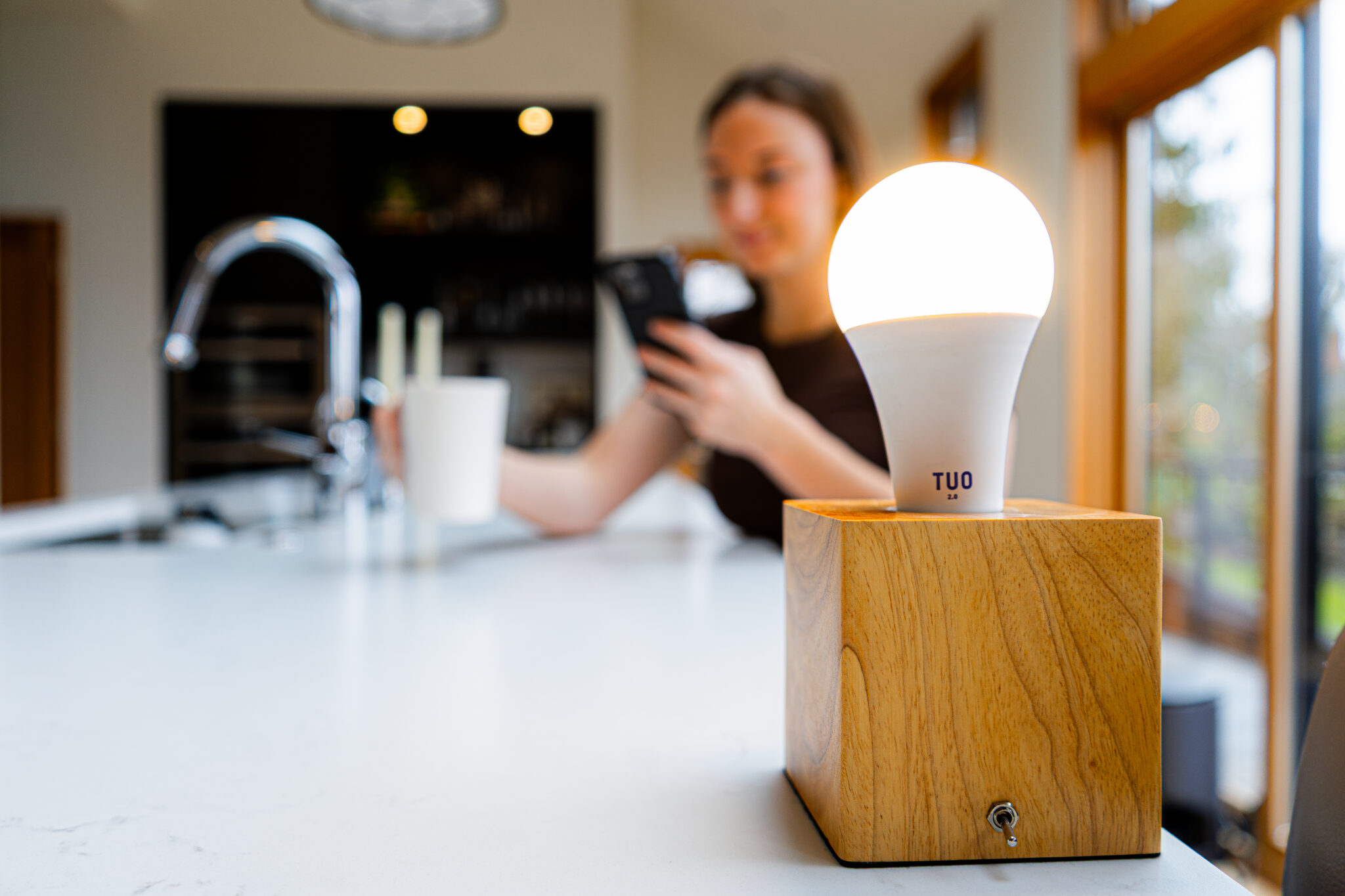light bulb in kitchen with woman drinking coffee in background in kitchen