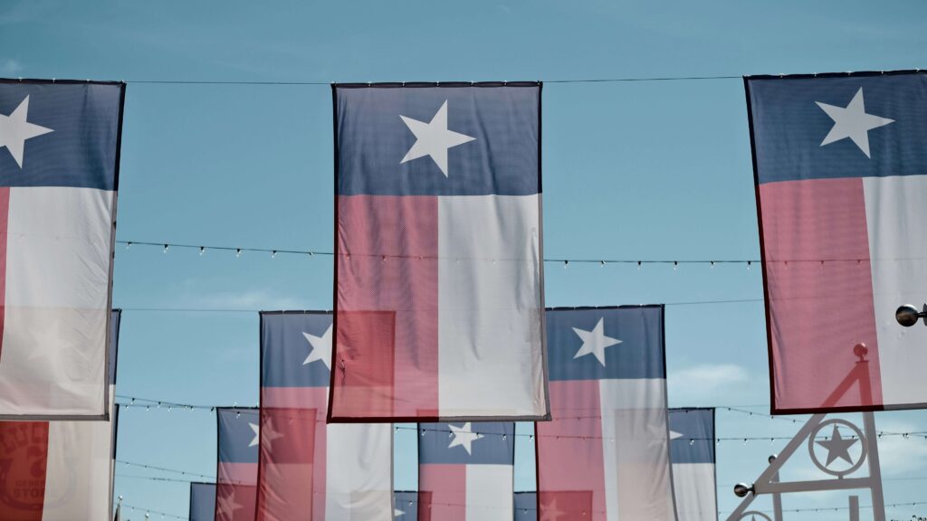 Banderas de Texas colgadas sobre una calle con un cielo azul de fondo