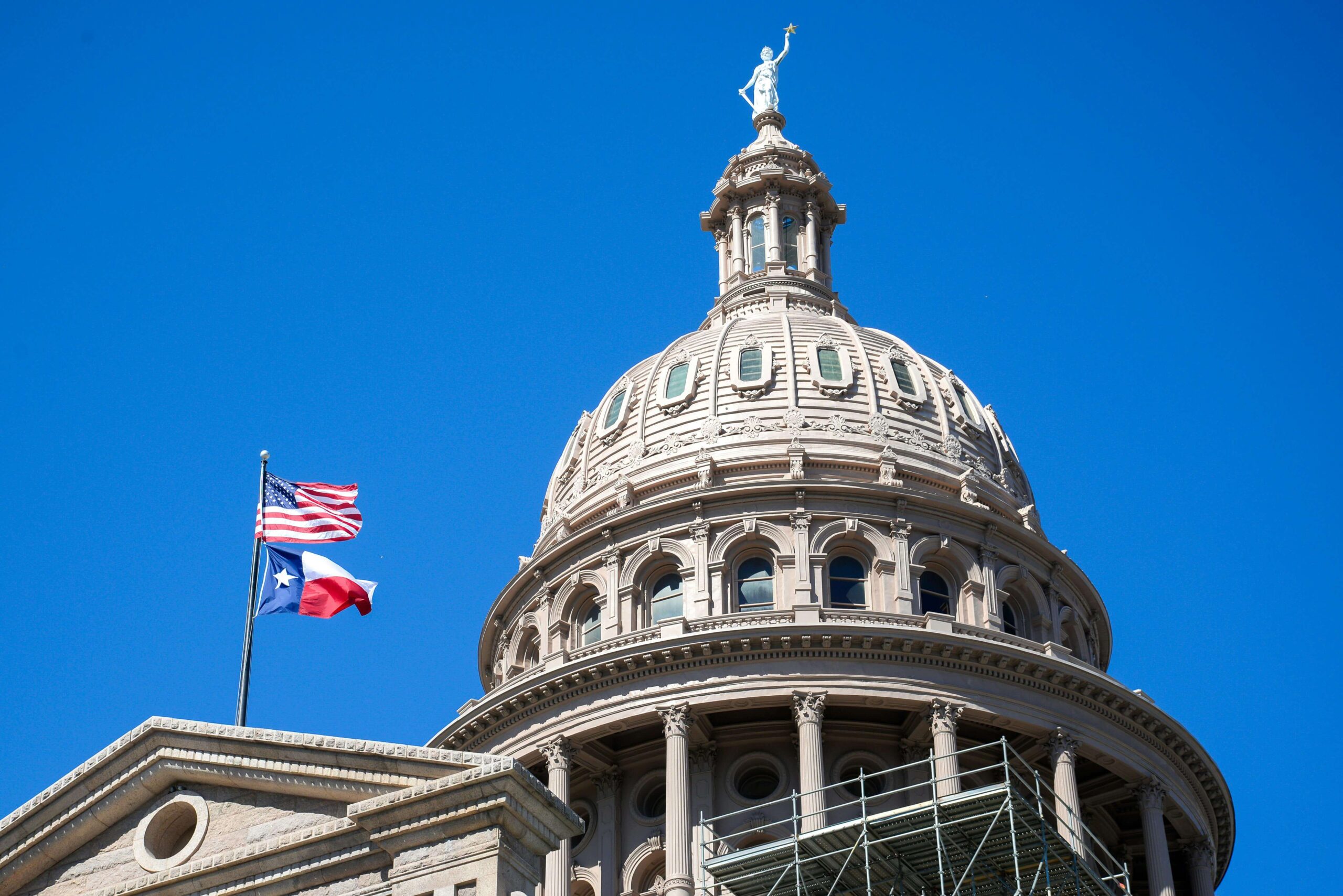 The flags of the U.S. and Texas flying at the Austin Capitol building where Houston adjustment of status attorneys meet.