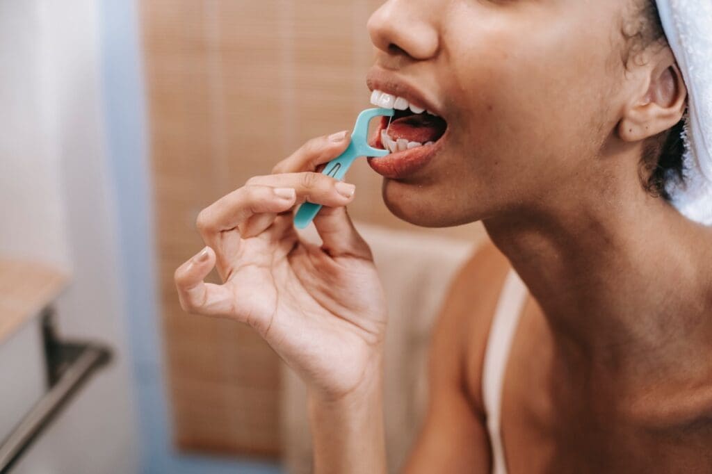 a young woman looks in the mirror and flosses her teeth