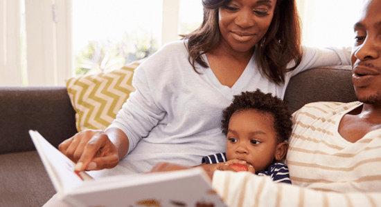 Family of three reading together on a couch.