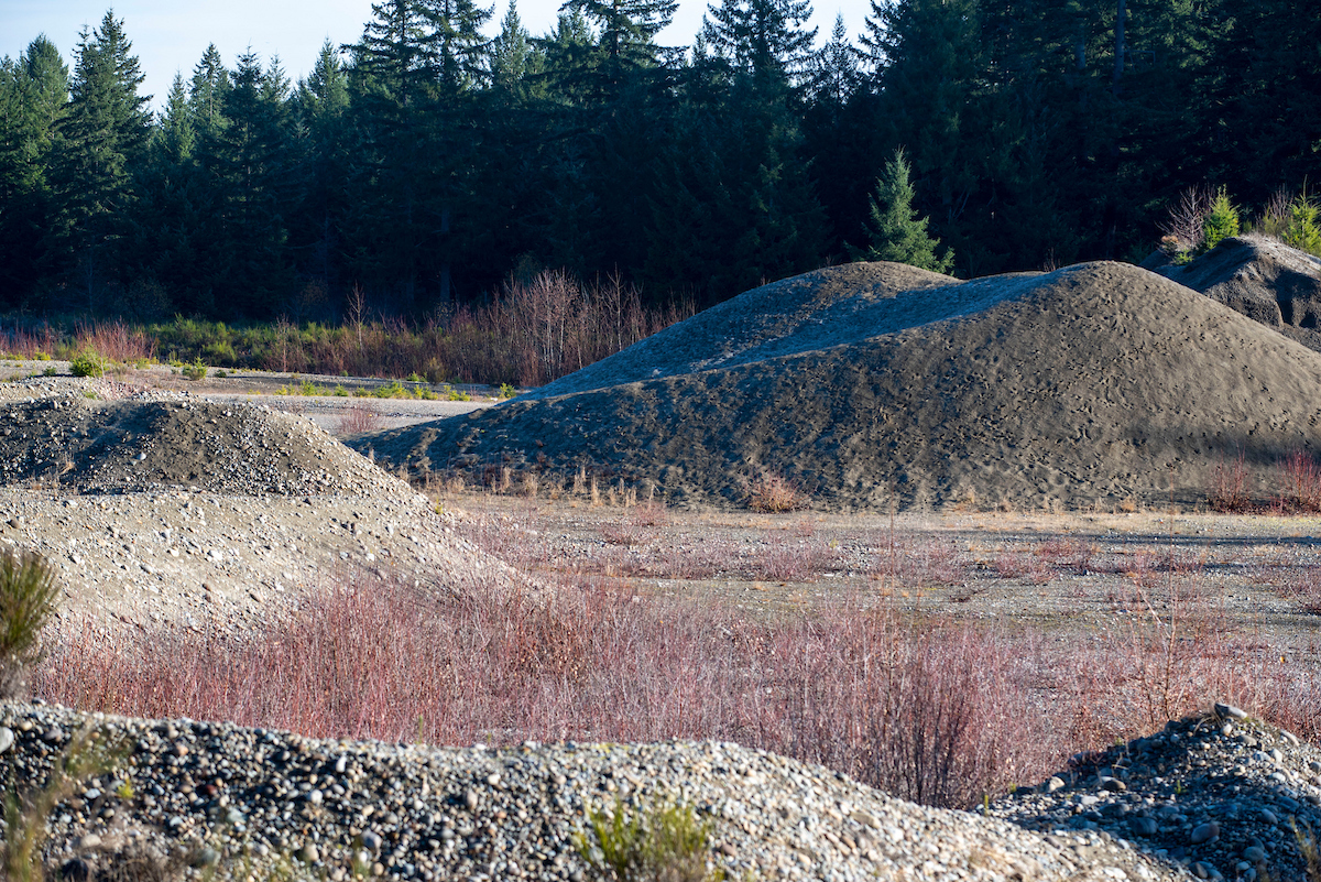Hills of gravel surrounded by brush.