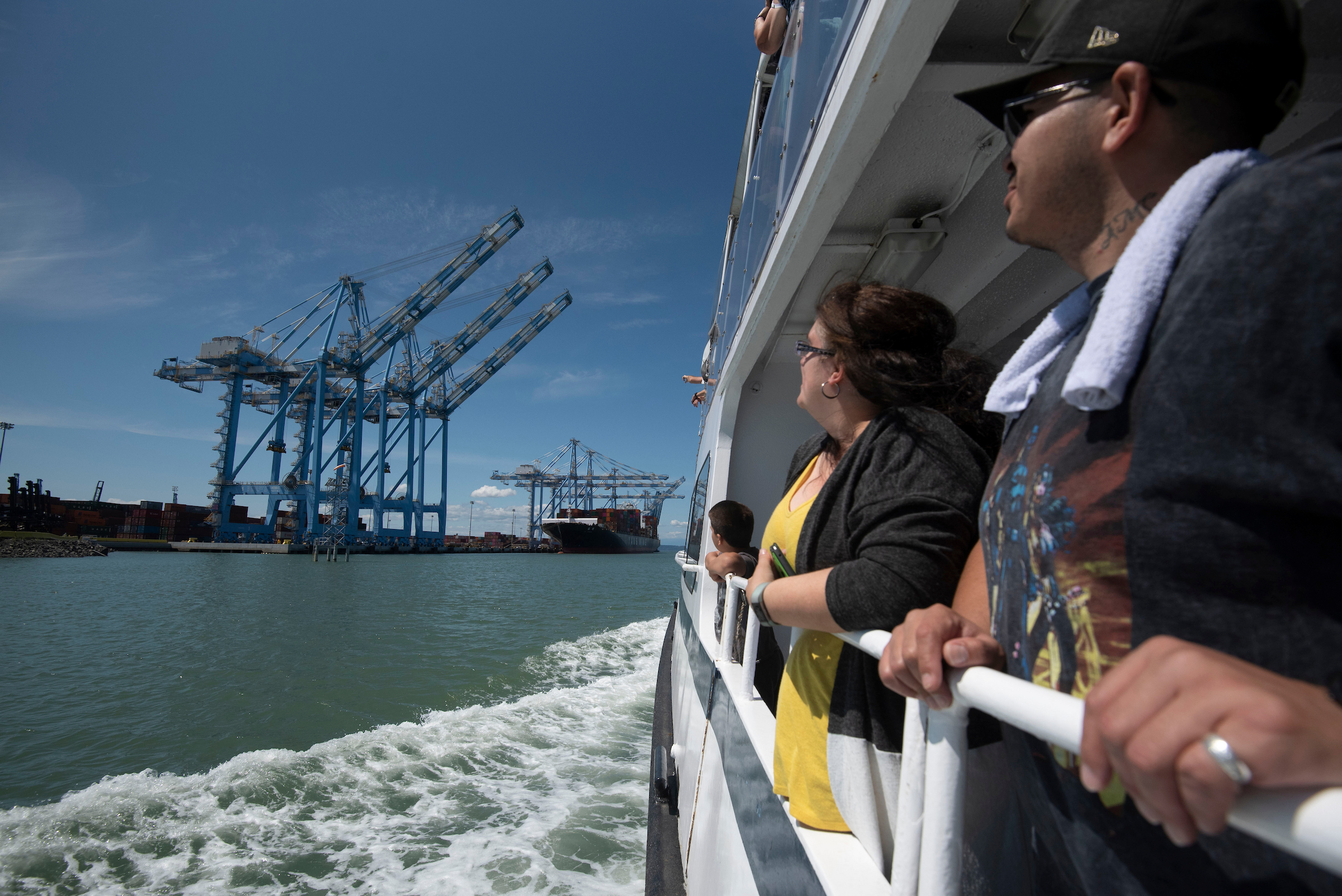A man and woman hold the railing of a boat to look at blue cranes.
