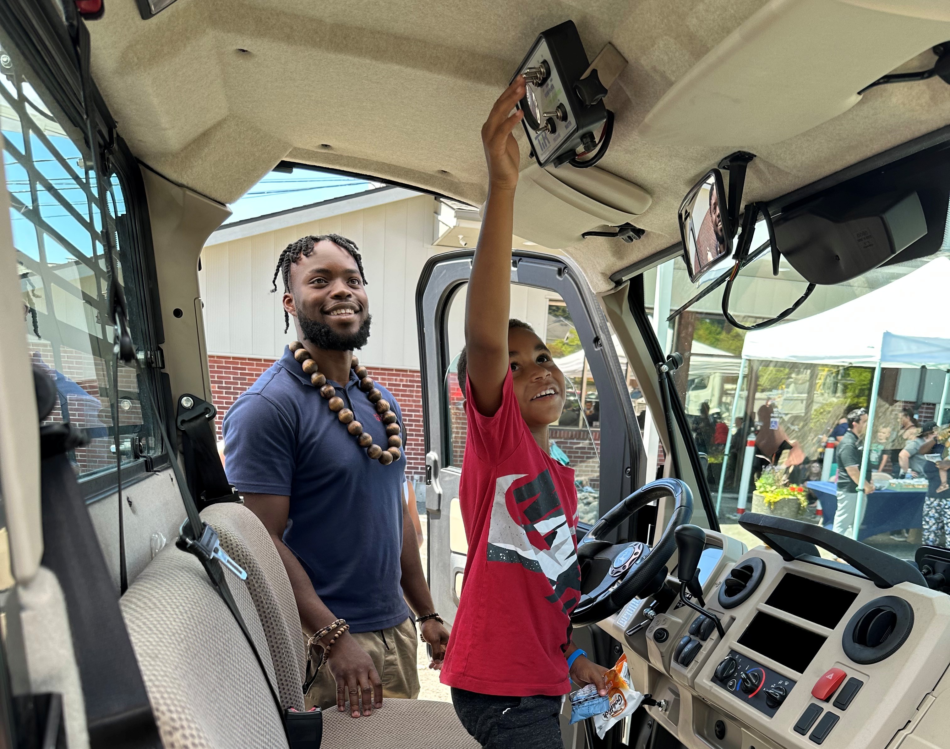 A man and young boy look at the inside of a large truck.