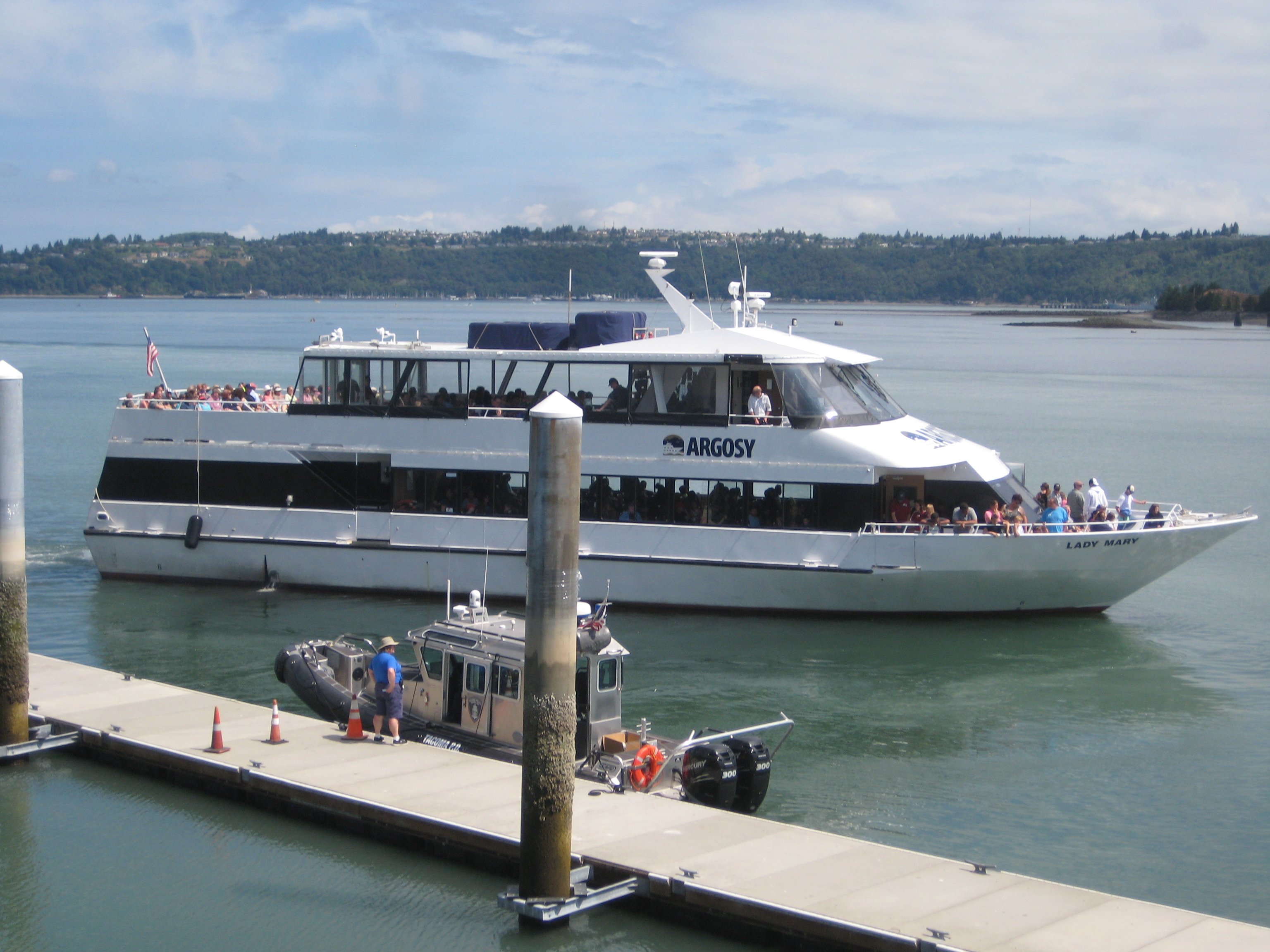 A small cruise ship pulling away from a dock. 