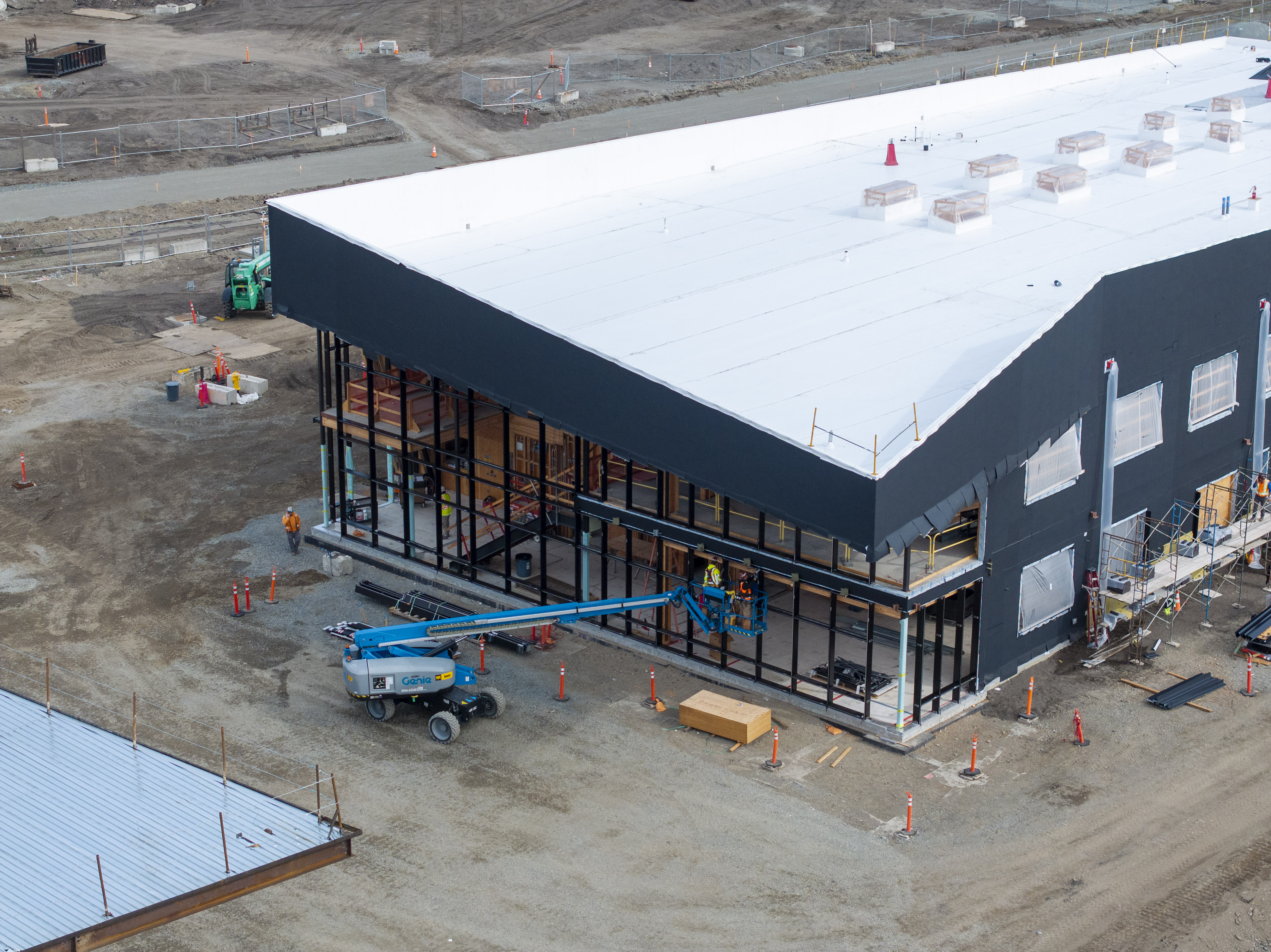 Aerial shot of a building with a white roof being constructed.