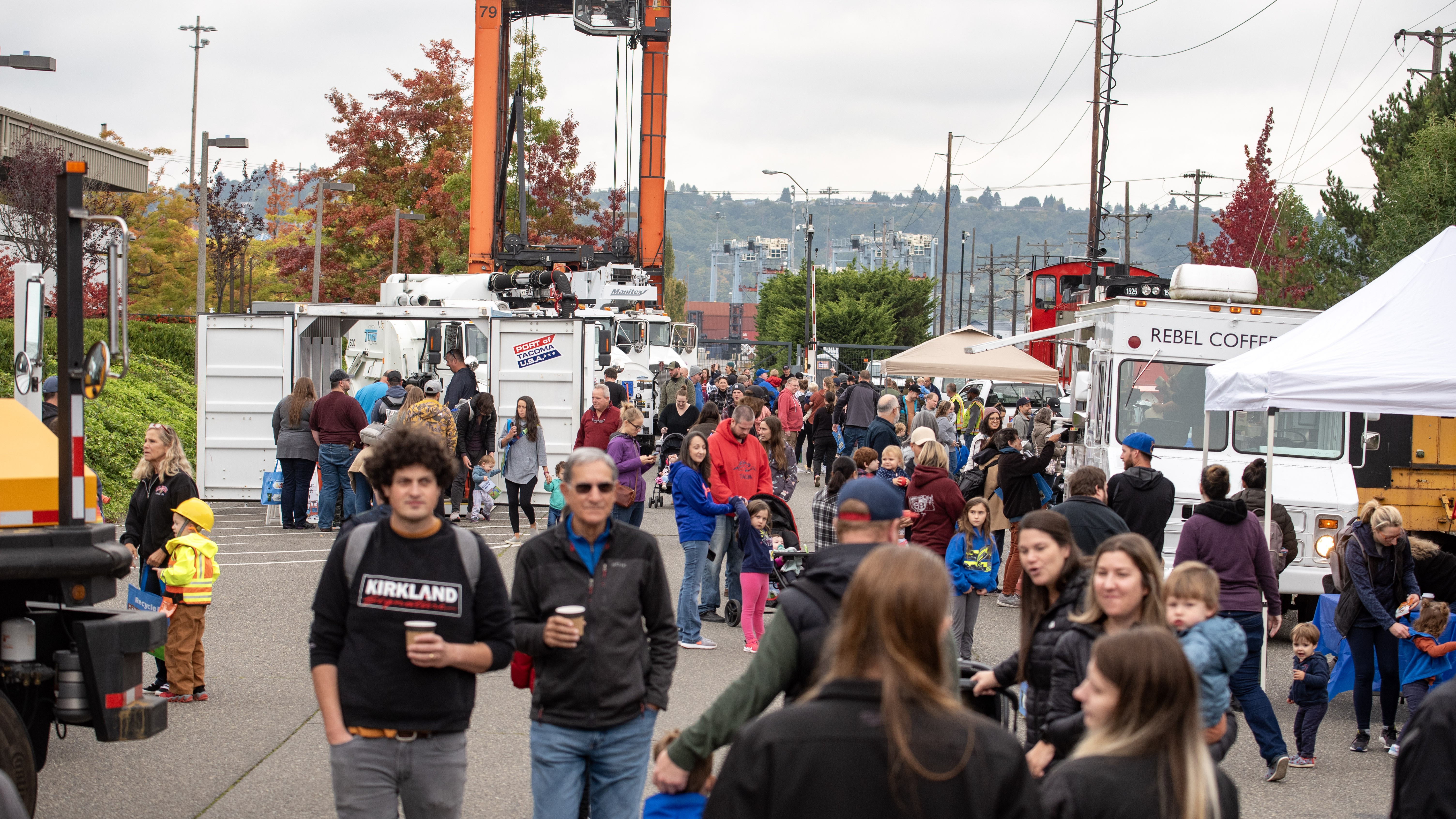 A group of people walking through a Port Touch a Truck event. 