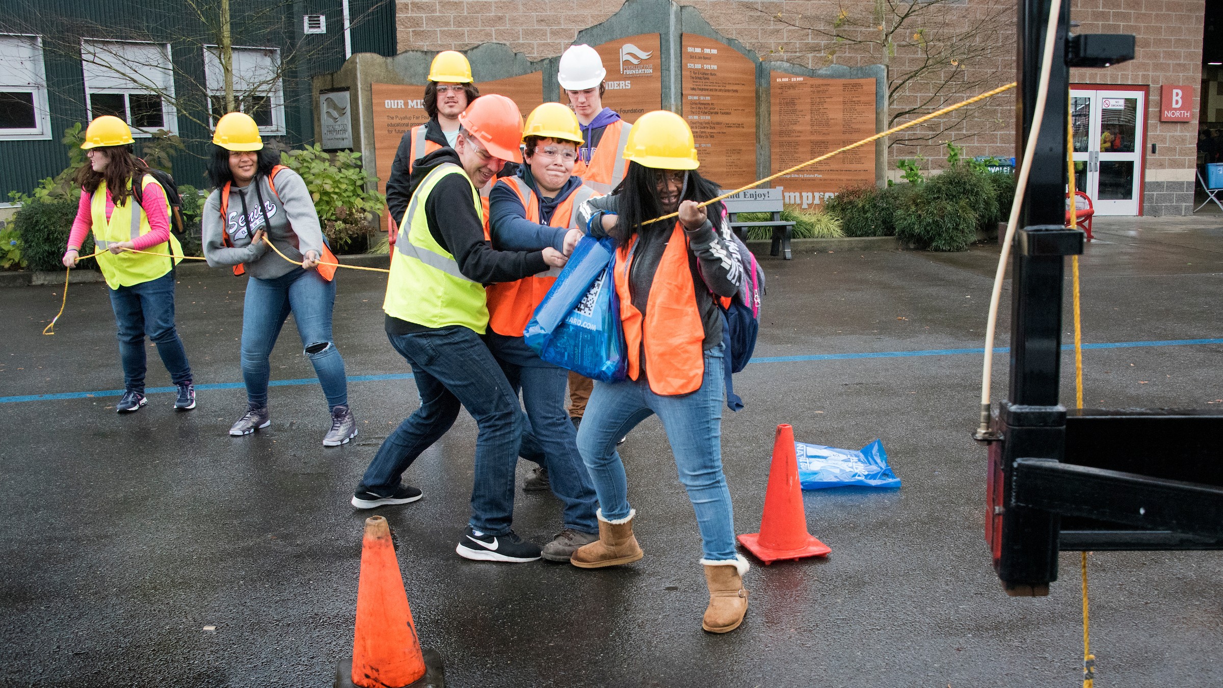 A group of students in protective gear pull a rope together.