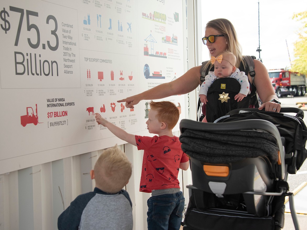 A young mother and her child point to a sign with facts about the Port. 