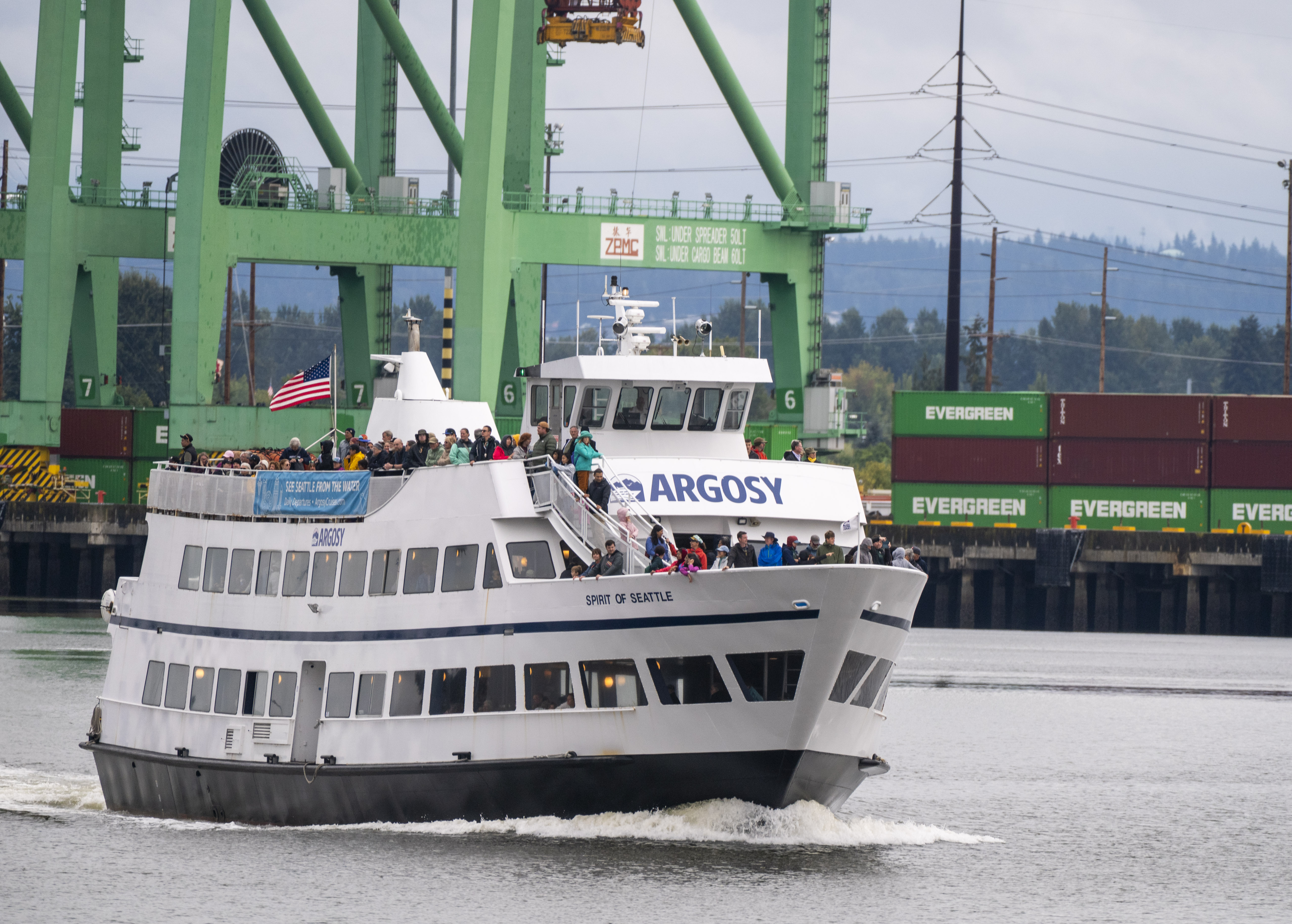 An Argosy cruise ship full of people move through a waterway on a Port boat tour.