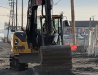 An excavator digs into dirt at a construction site.